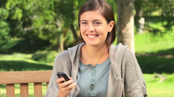 Joyeux jeune femme sur un banc — Video