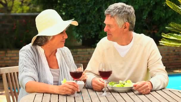 Ώριμο ζευγάρι τσούγκριζαν ποτήρια κόκκινο κρασί στον κήπο τους — Αρχείο Βίντεο