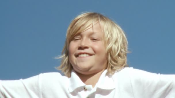Lächelnder blonder Junge springt — Stockvideo