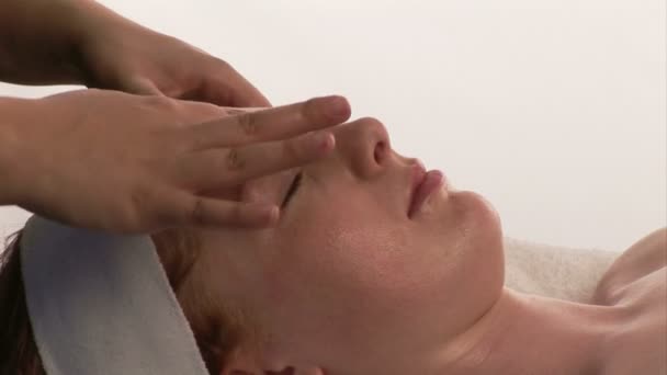 Uma mulher recebendo uma massagem facial — Vídeo de Stock