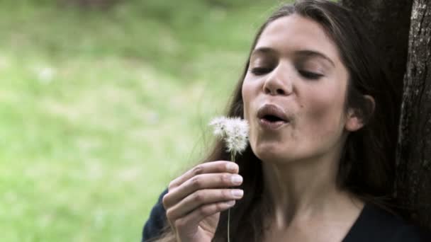 Ontspannen vrouw in slow motion waait een paardebloem — Stockvideo