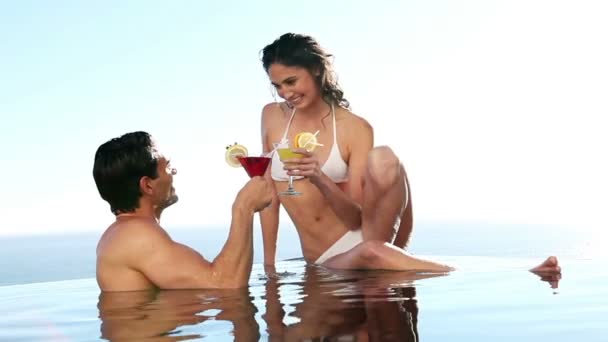 Cuplu într-o piscină care bea cocktail-uri — Videoclip de stoc