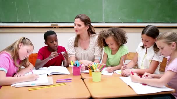 Учитель сидит за столом с учениками — стоковое видео