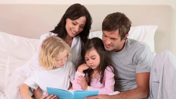 Children reading a book with their parents — Stock Video