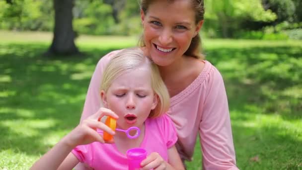 Menina soprando bolhas com sua mãe — Vídeo de Stock
