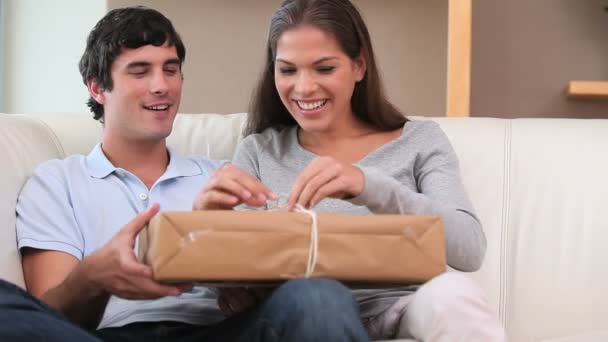 笑みを浮かべてカップルの贈り物をアンラッピング — ストック動画