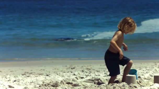 Ребенок в замедленной съемке разрушает песчаный замок — стоковое видео