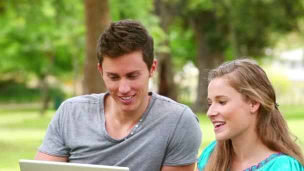 Woman laughing as she watches a laptop with her friend before playfully pushing him — Stock Video