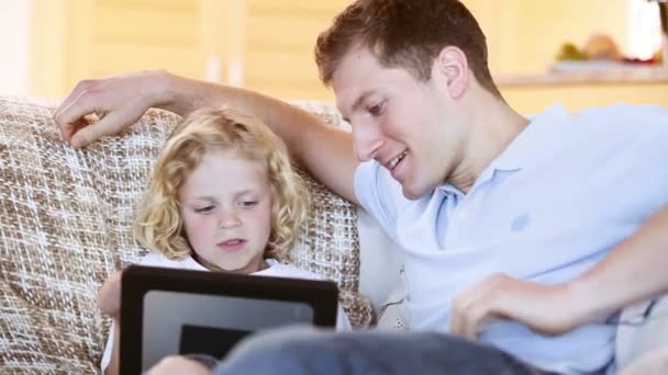 Glimlachend vader met behulp van een tablet pc met zijn zoon — Stockvideo
