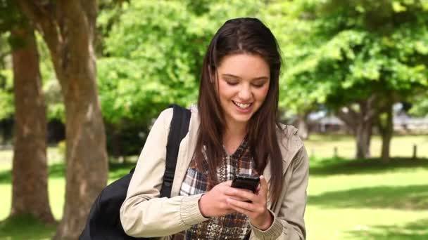 Mulher rindo enquanto lê uma mensagem de texto em seu celular — Vídeo de Stock