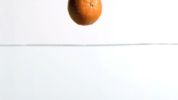 Апельсин падает в воду в замедленной съемке — стоковое видео