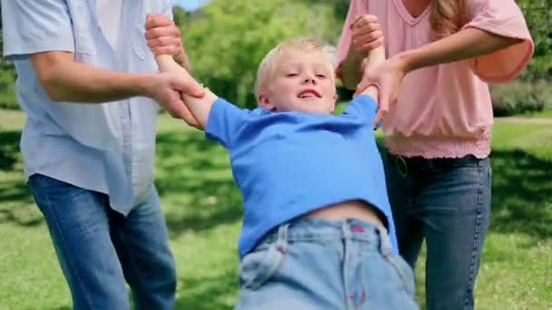 Boy being swung back and forth by his parents who are holding his arms — Stock Video