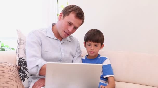 Otec a syn s notebookem v obývacím pokoji — Stock video