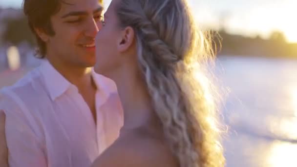 Paar draaien en zoenen tijdens zonsondergang voordat ze naar de zee lopen — Stockvideo