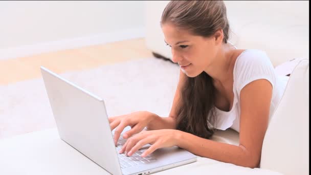 Mujer morena mintiendo mientras usa su computadora portátil — Vídeo de stock