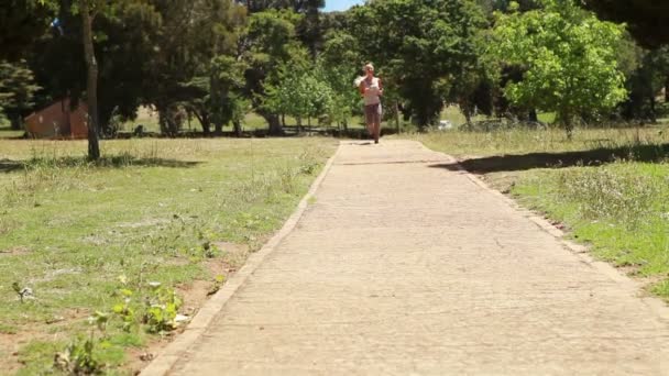 Bir kadın bir patika kamera geçmiş ve doğru yukarı jogs — Stok video