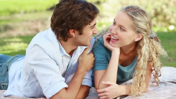 A couple lying on the ground share a kiss and then look at the camera — Stock Video