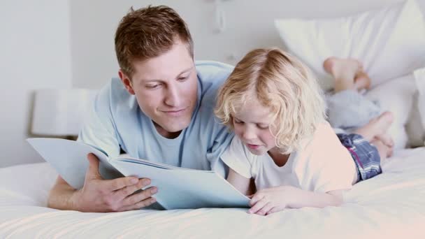 Father and son smiling while reading a book — Stock Video