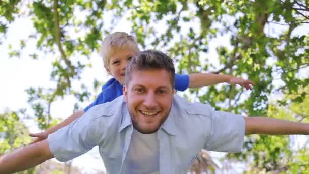 Padre le da a su hijo un cerdito mientras tienen los brazos abiertos antes de sostenerlo — Vídeos de Stock