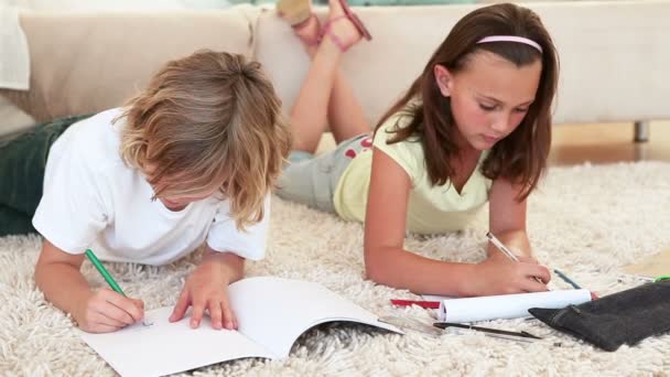 Hermano y hermana haciendo tareas en el piso de la sala de estar — Vídeos de Stock