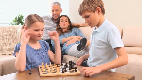 Sérieux frères et sœurs jouant aux échecs — Video