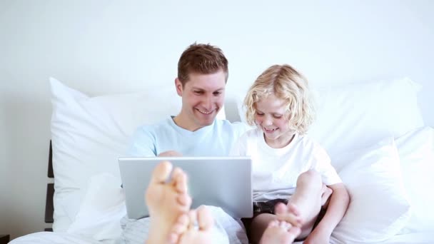 Sorrindo pai e filho olhando para um laptop — Vídeo de Stock