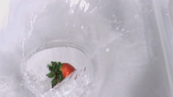 Клубника падает в воду в замедленной съемке — стоковое видео