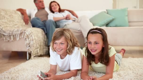 Frères et sœurs allongés en regardant la télévision — Video