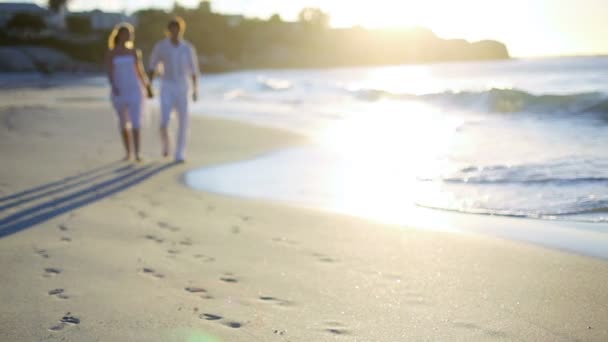 Paar hand in hand als ze uit de buurt van de zonsondergang op het strand lopen — Stockvideo