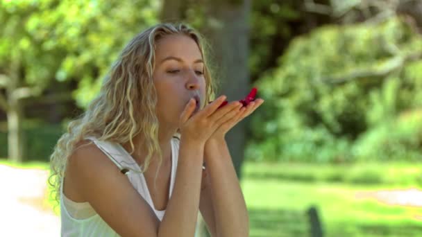 Blonde vrouw waait in slow motion op bloemblaadjes — Stockvideo