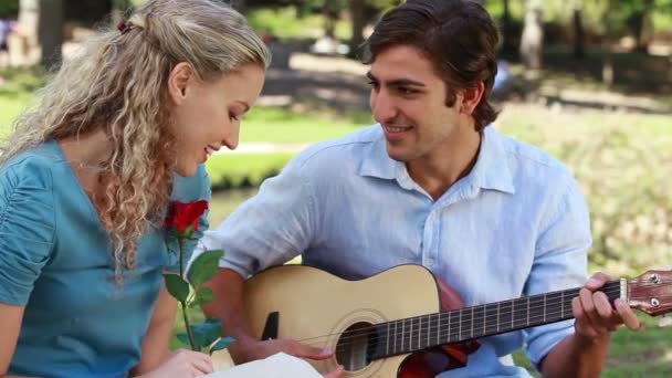 Namorado toca guitarra para sua namorada como ela segura uma rosa e, em seguida, beijar — Vídeo de Stock