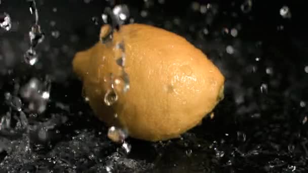 Вода льется на лимон в очень медленном темпе — стоковое видео