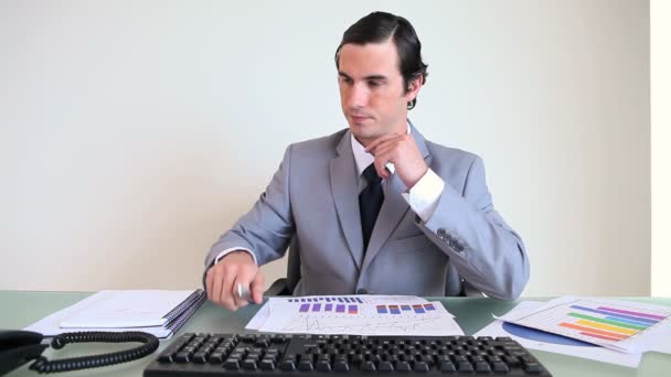 Businessman working while picking up the phone — Stock Video