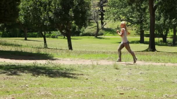 Une femme court sur un sentier dans le parc — Video