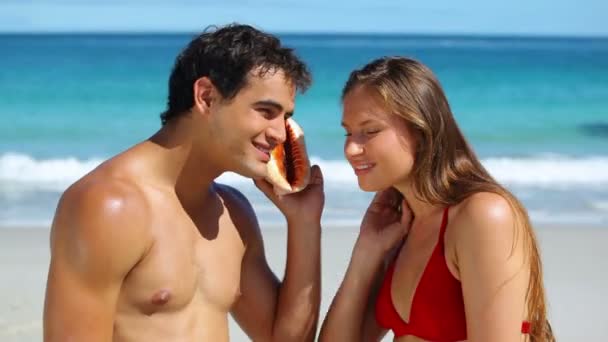 Pareja escuchando el agua con una concha — Vídeos de Stock