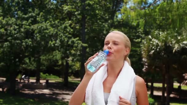 En kvinna går och tar en drink innan torka huvudet och gå igen — Stockvideo