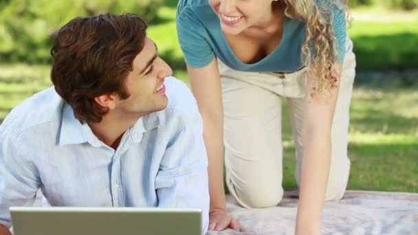 Woman lies down beside her boyfriend as they watch a laptop and then look into the camera — Stock Video