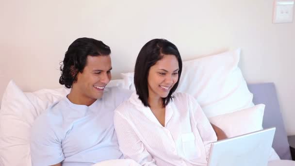 Casal sentado na cama com laptop — Vídeo de Stock