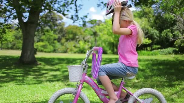 Flickan sätter på en cykel hjälm och håller styret — Stockvideo