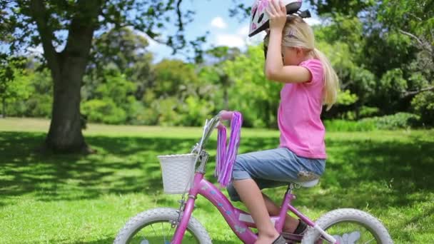 Chica se pone un casco de ciclismo y sostiene las barras de mango — Vídeo de stock