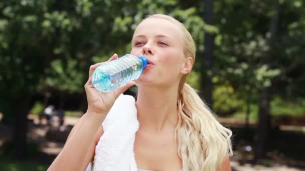 Una donna beve un sorso d'acqua e si pulisce la testa prima di bere di nuovo — Video Stock