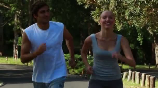 Um casal sorrindo olha um para o outro enquanto eles correm — Vídeo de Stock