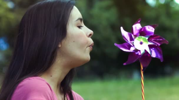 Vrouw ademhaling op een pinwheel in slow motion — Stockvideo