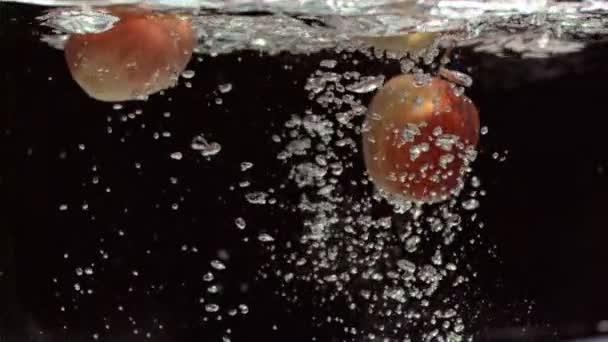 Яблоки движутся под водой в супер медленном движении — стоковое видео