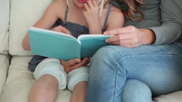 Chica riendo como ella está leyendo un libro con su madre — Vídeos de Stock