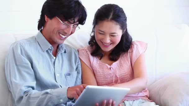 Pareja sonriendo mientras usan una tableta — Vídeos de Stock