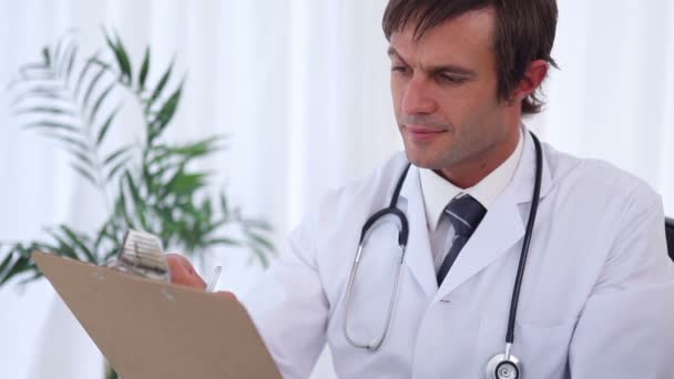 Good-looking doctor writing on a clipboard — Stock Video