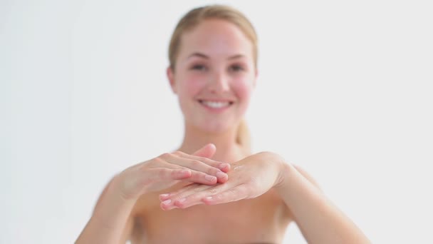 Lachende vrouw vochtinbrengende crème toe te passen op haar hand — Stockvideo