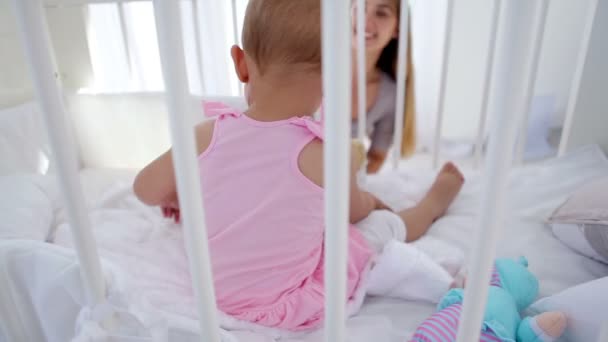 Menina em um berço brincando com sua mãe — Vídeo de Stock