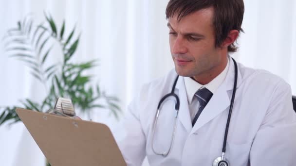 Doctor writing on a clipboard while sitting — Stock Video